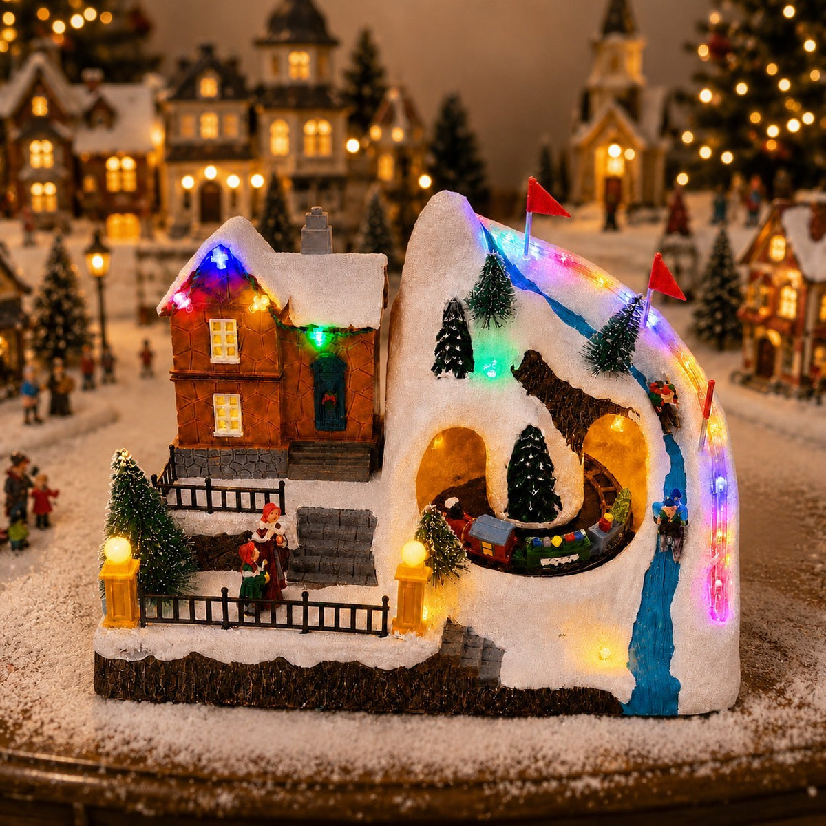 Illuminated Christmas ski resort village with a miniature train, snowy mountain and colorful holiday lights