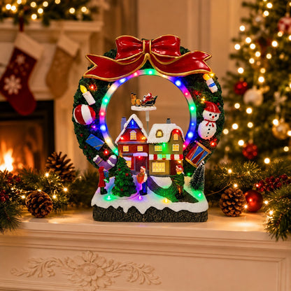 Lighted Christmas wreath village scene on a windowsill with Santa sleigh and snowy houses