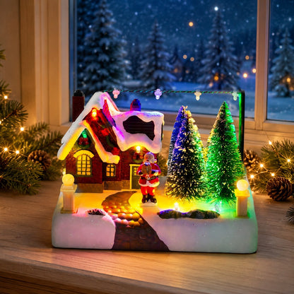 Lighted resin Christmas village house with Santa displayed on a festive indoor tabletop