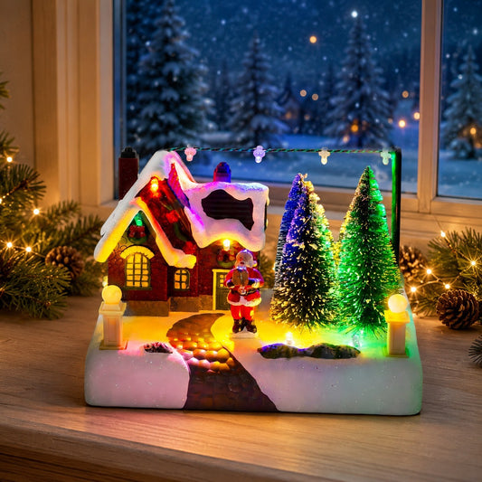 Lighted resin Christmas village house with Santa displayed on a festive indoor tabletop