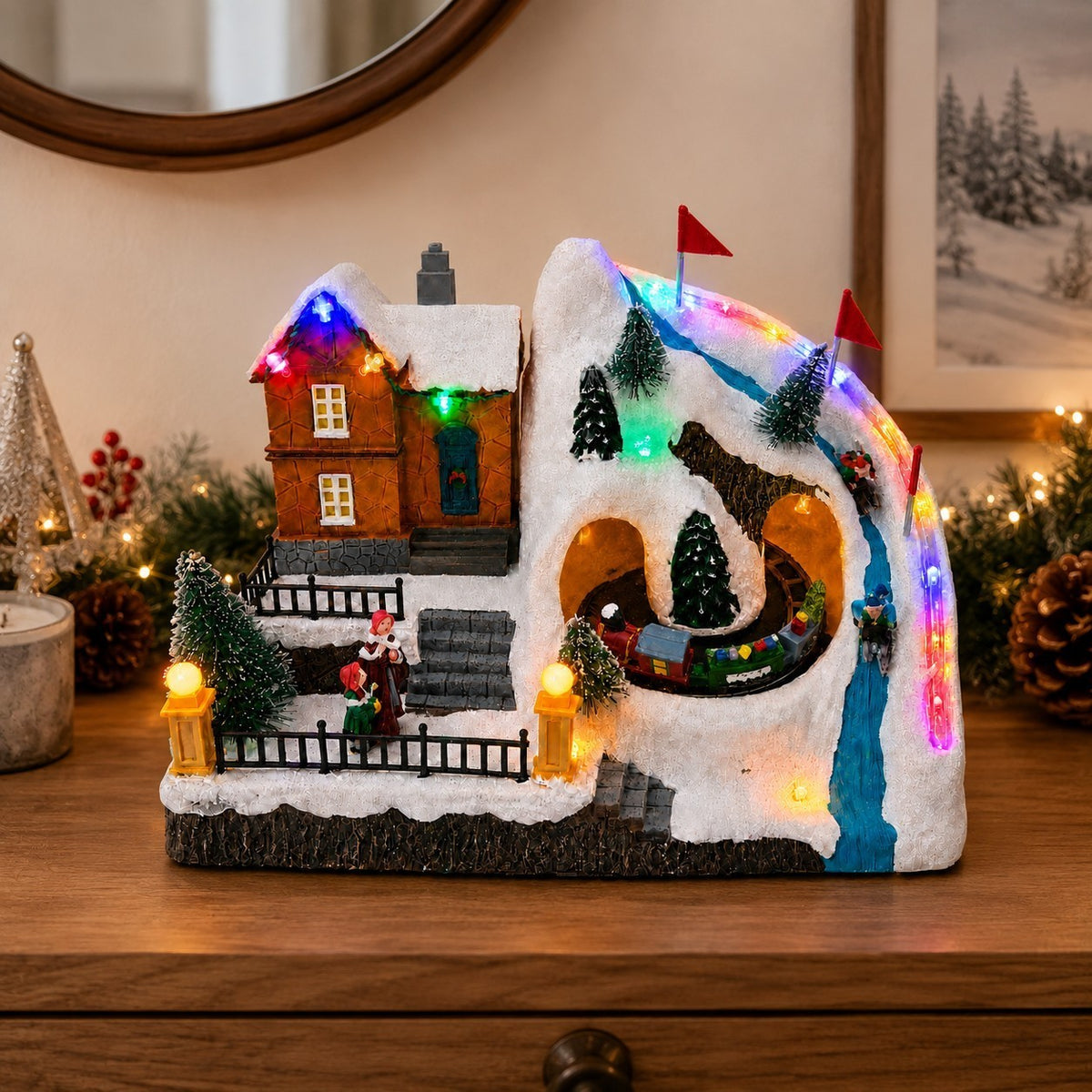 Battery-operated Christmas ski village displayed on a wooden table with festive decorations