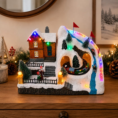 Battery-operated Christmas ski village displayed on a wooden table with festive decorations